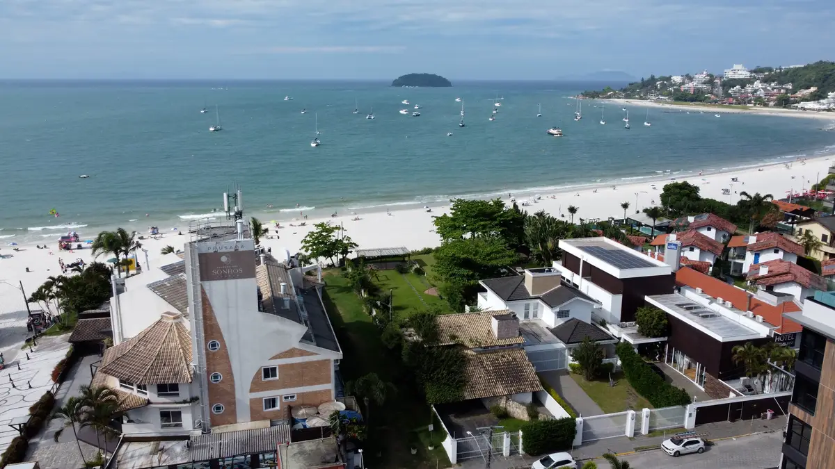 Vista aérea da praia com casas, prédios e barcos no mar de Jurerê Internacional